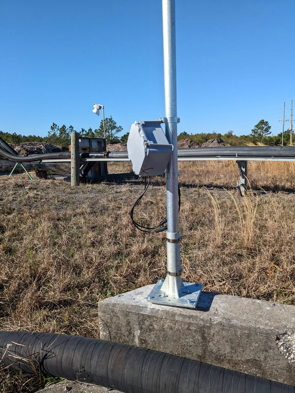 EOS2 sensor pole bolted to a concrete barrier with a weatherproof power enclosure