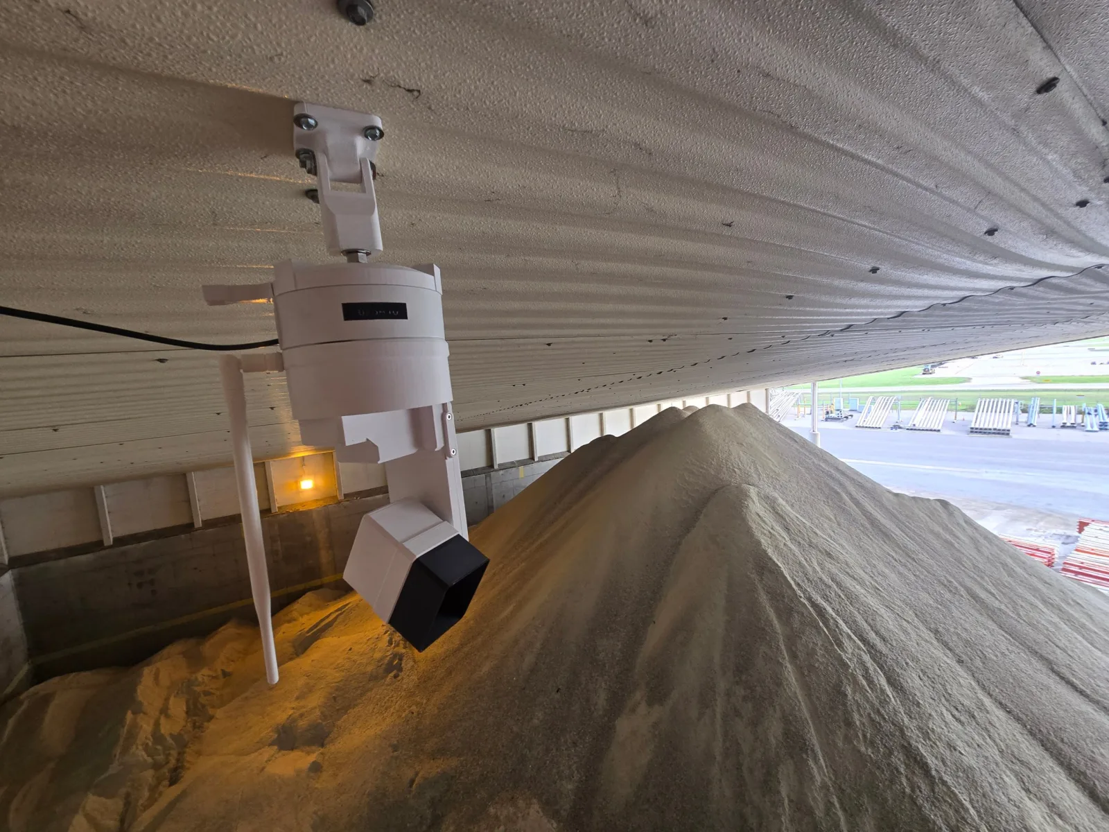 EOS2 LiDAR sensor mounted under the roof of a salt storage shed, looking down on a road salt stockpile with the truck yard visible outside